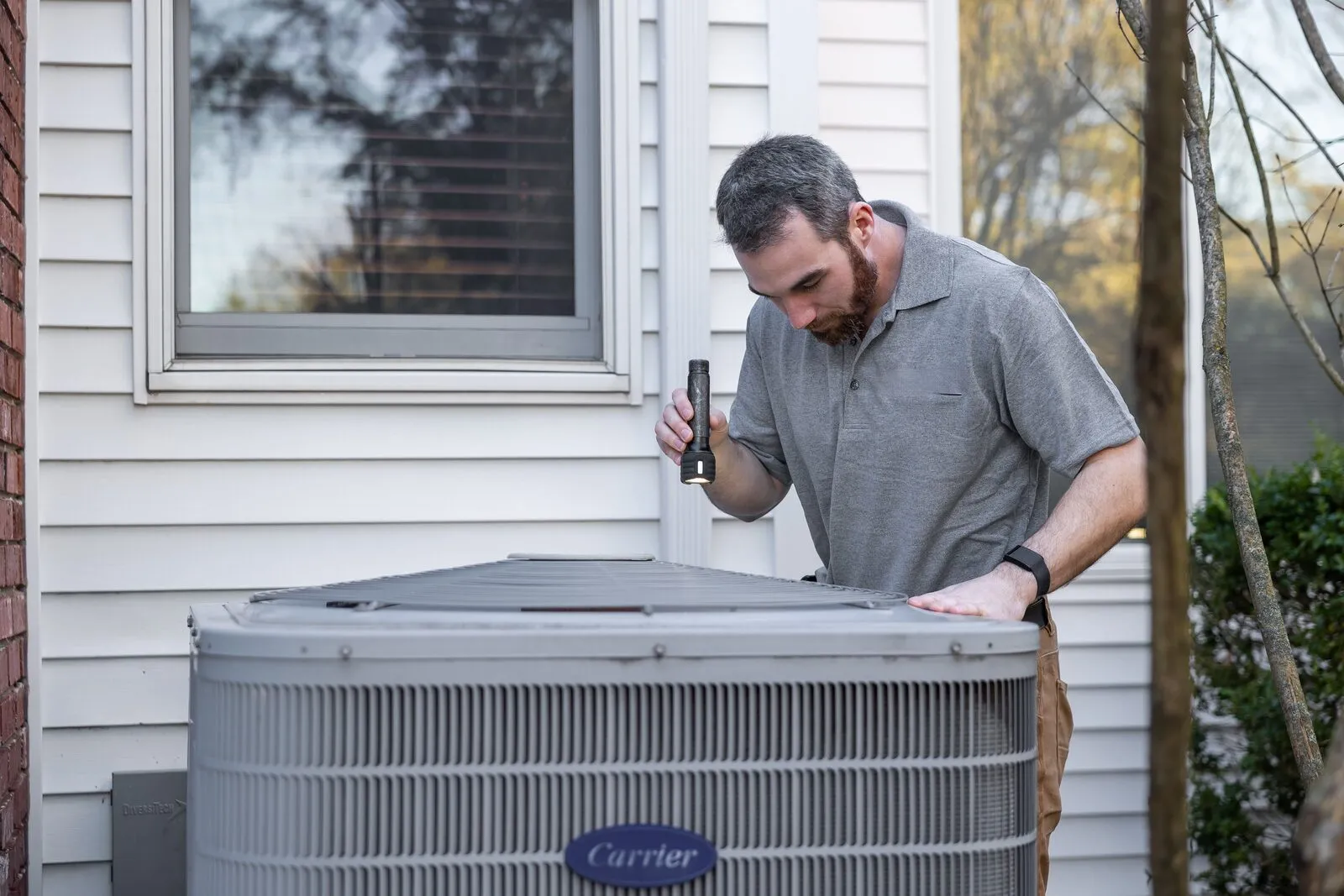 Illustrative stock photo — a technician inspecting an outdoor AC unit during maintenance; not an actual Lake Havasu AC Guide job site.